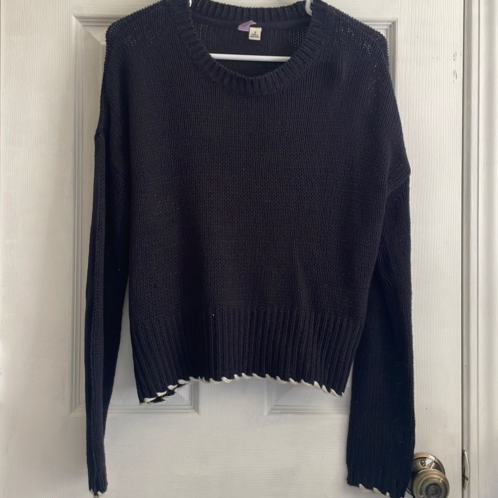 Loose, navy sweater with white detailing on edge of sleeves